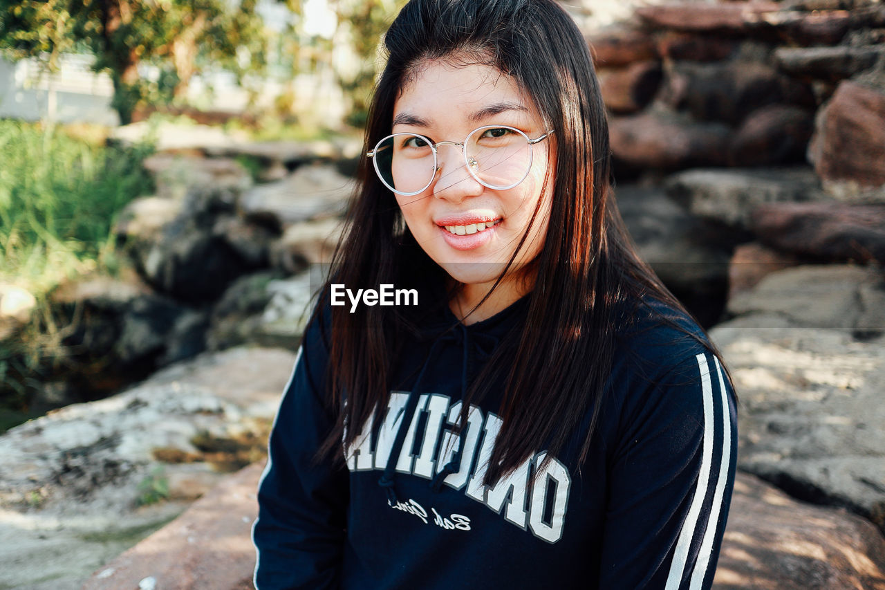 Portrait of smiling young woman standing on rock