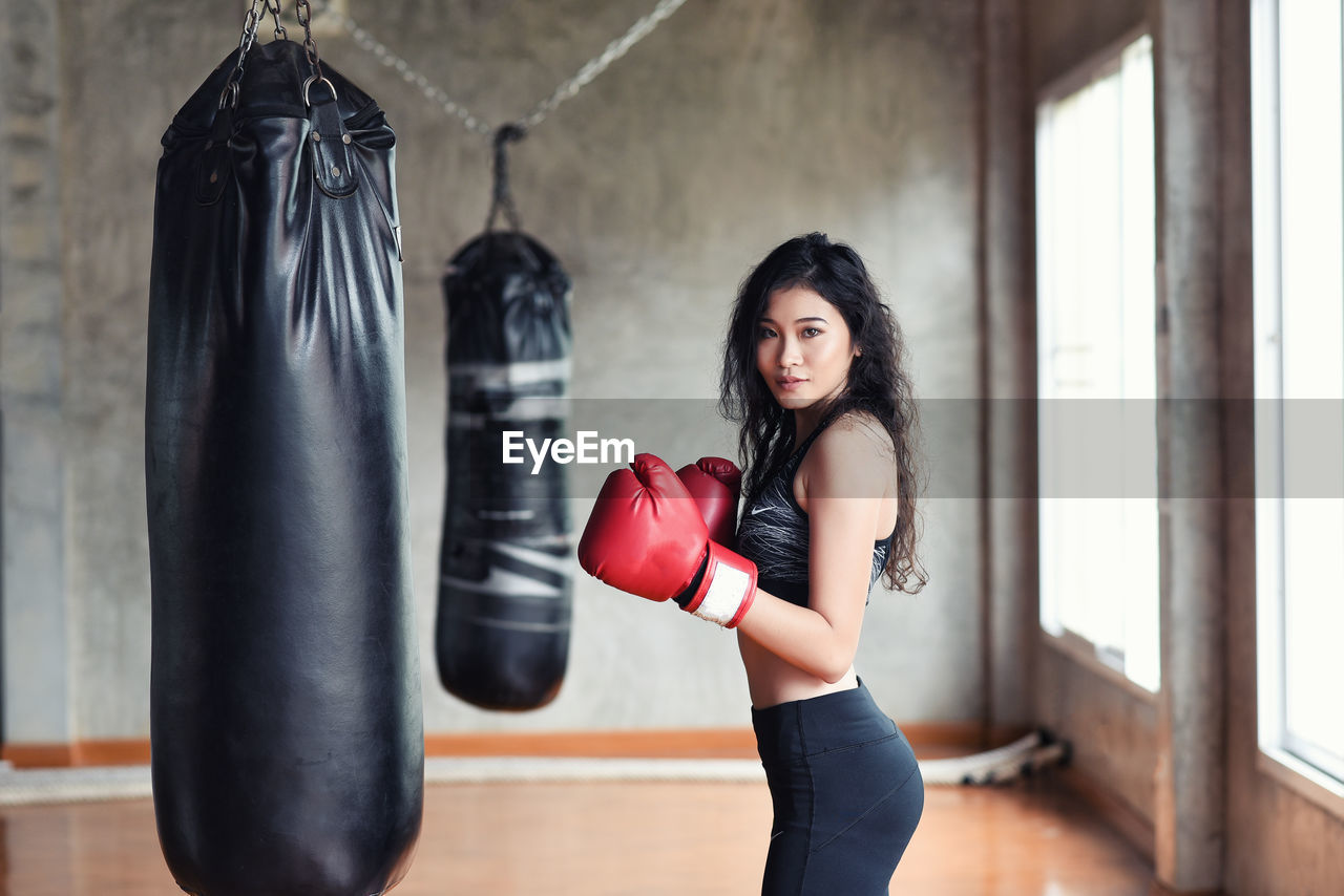 Portrait of young woman practicing with punching bag in studio