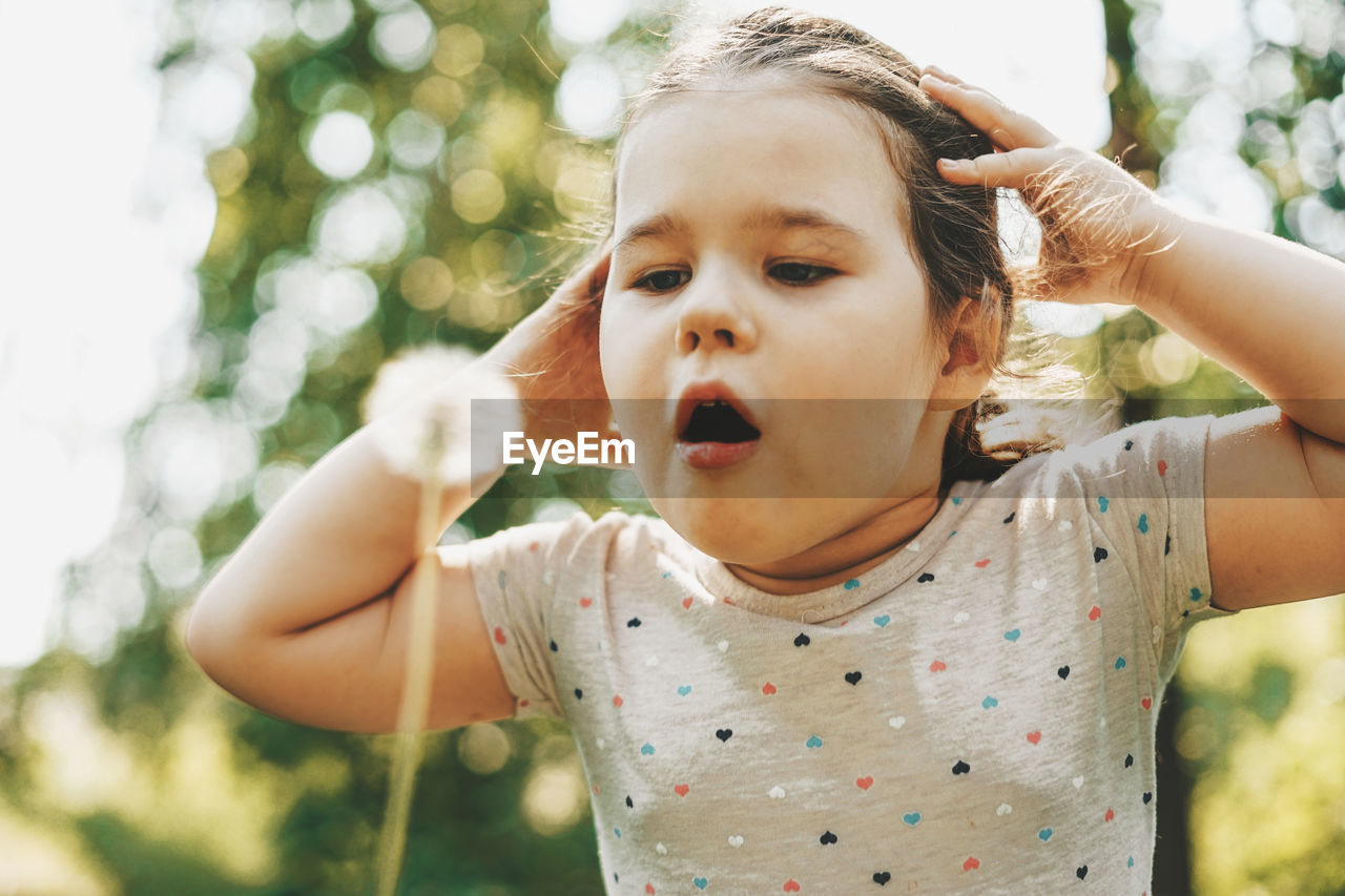 Close-up of cute girl blowing dandelion seed