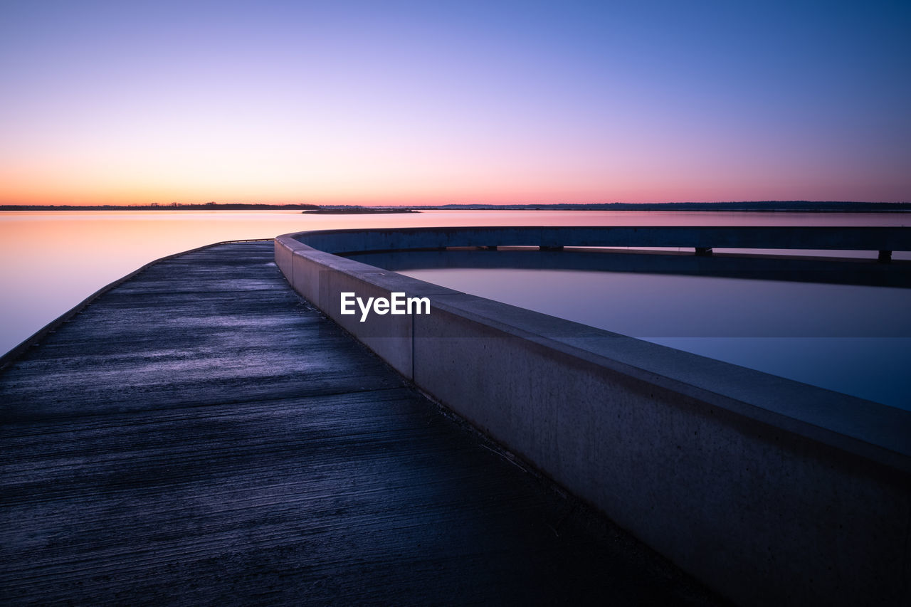 Bridge over sea against clear sky during sunset