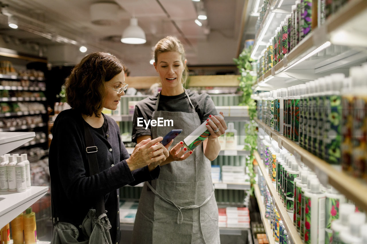 Saleswoman assisting female customer in supermarket