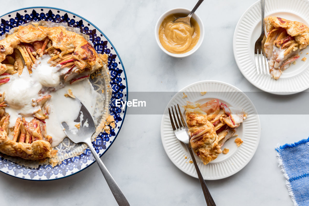 A salted caramel apple galette topped with melting ice cream and two servings.