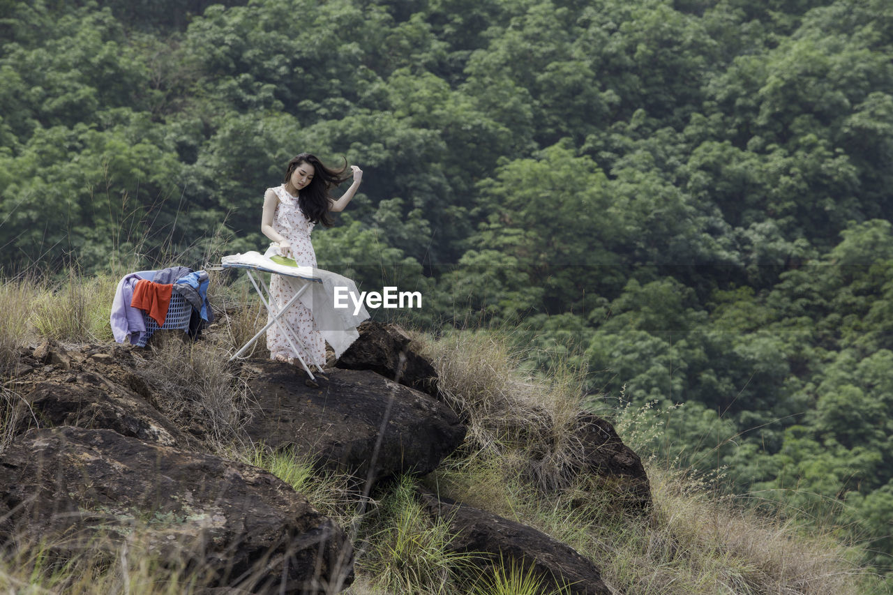 Woman ironing clothes in forest