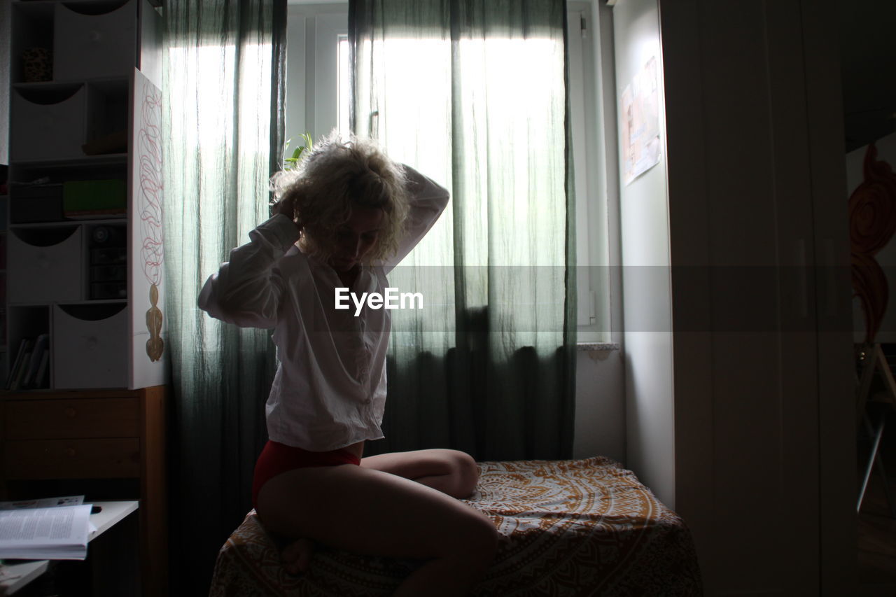 REAR VIEW OF GIRL SITTING ON BED