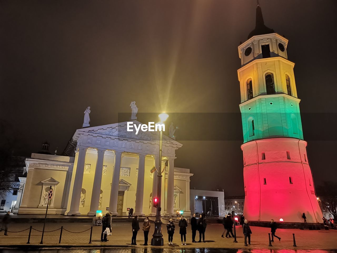 People by illuminated building in city at night