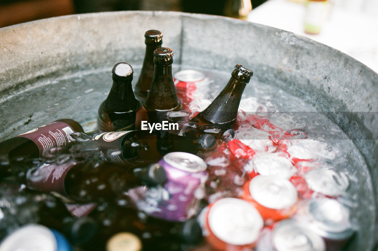 High angle view of bottles and drink cans in ice bucket