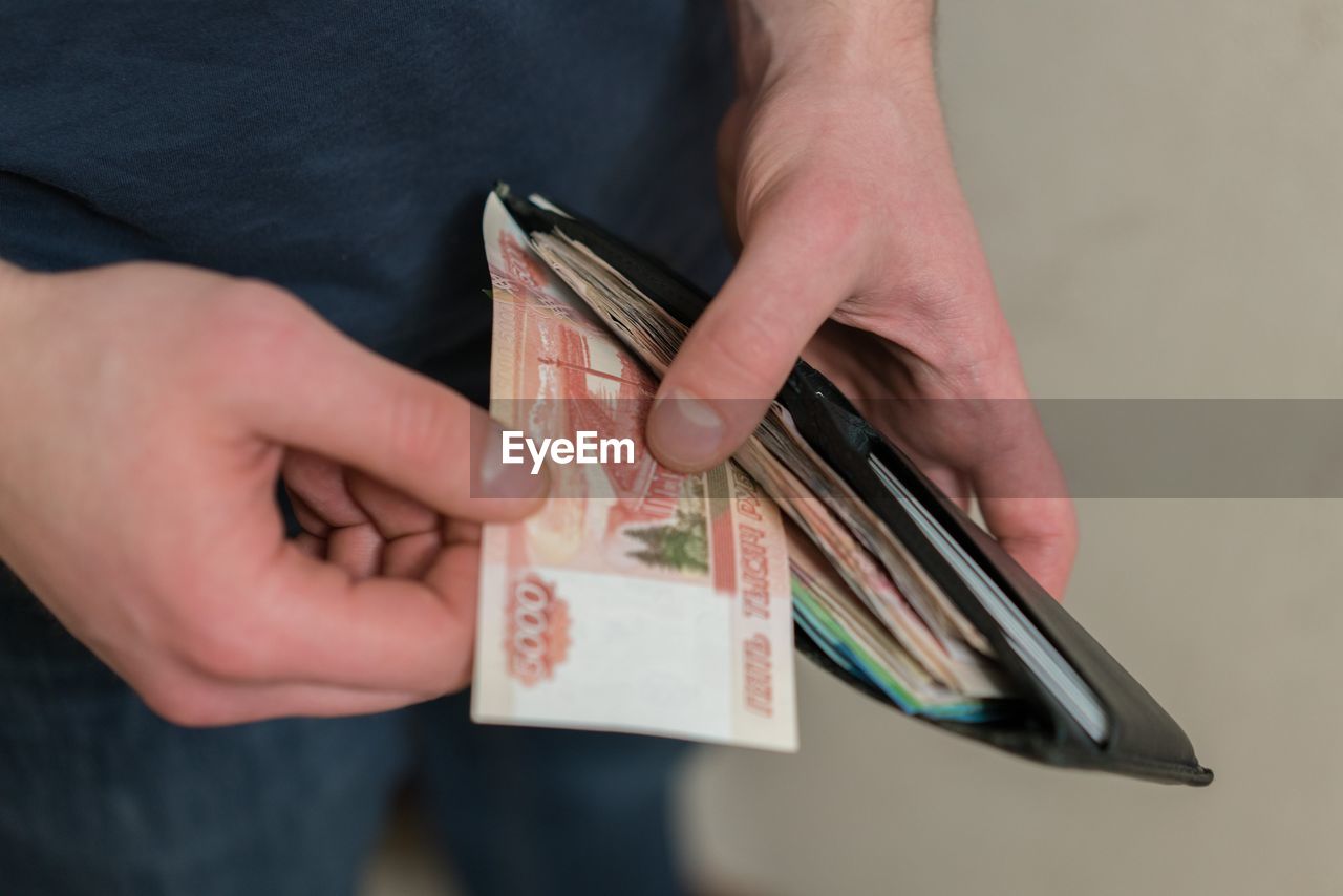 Midsection of man removing paper currency from wallet