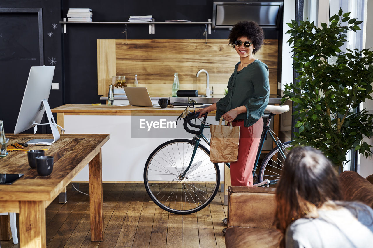 Young woman with bicycle arriving in modern office