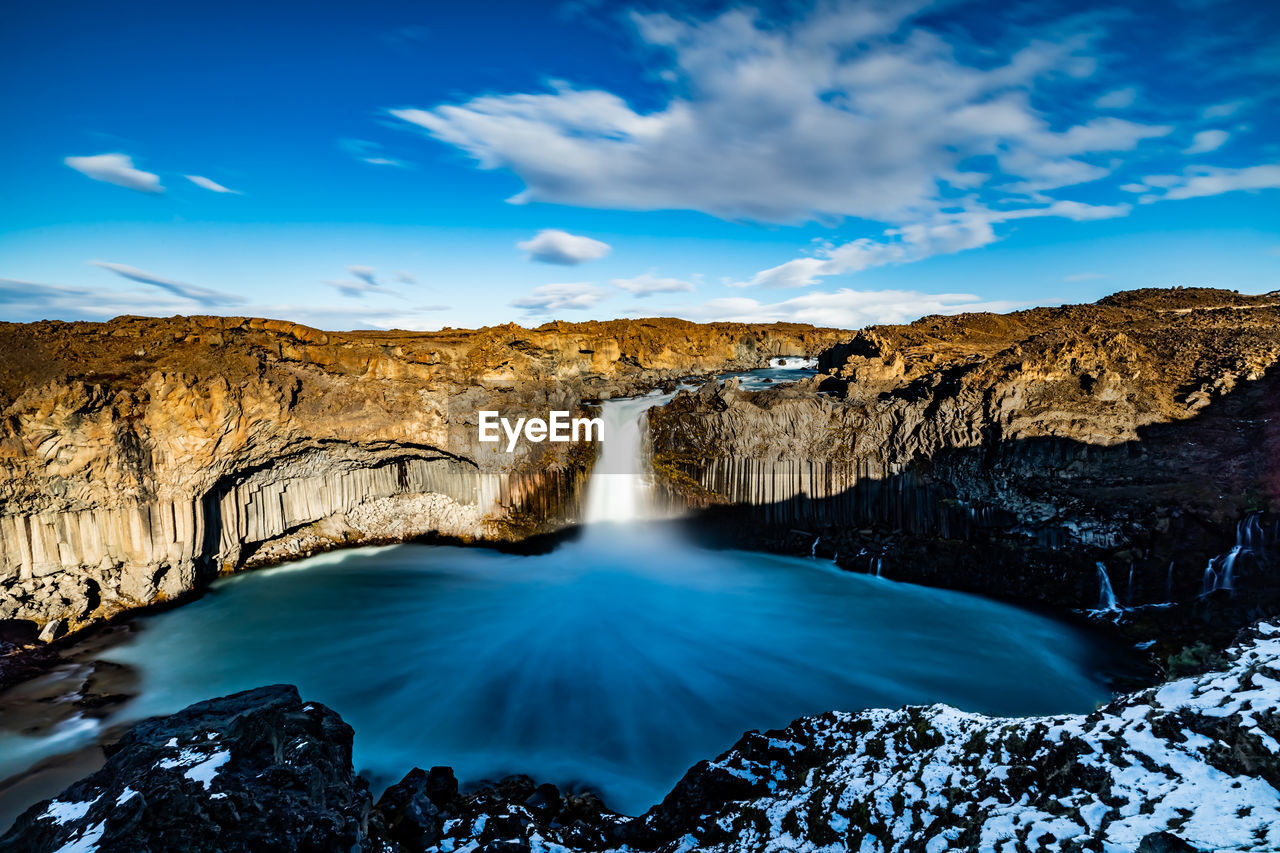 SCENIC VIEW OF WATERFALL AGAINST ROCKS