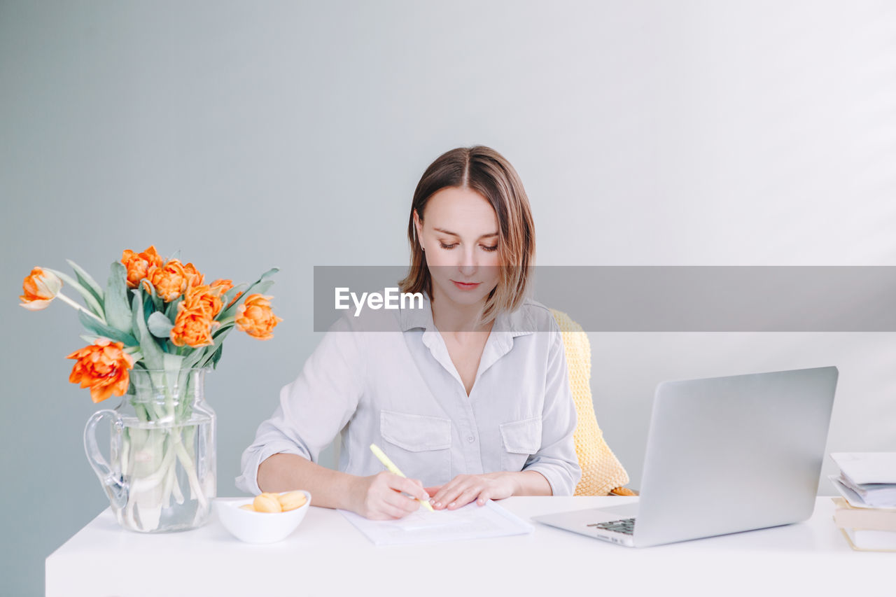 Businesswoman writing on document while sitting in office