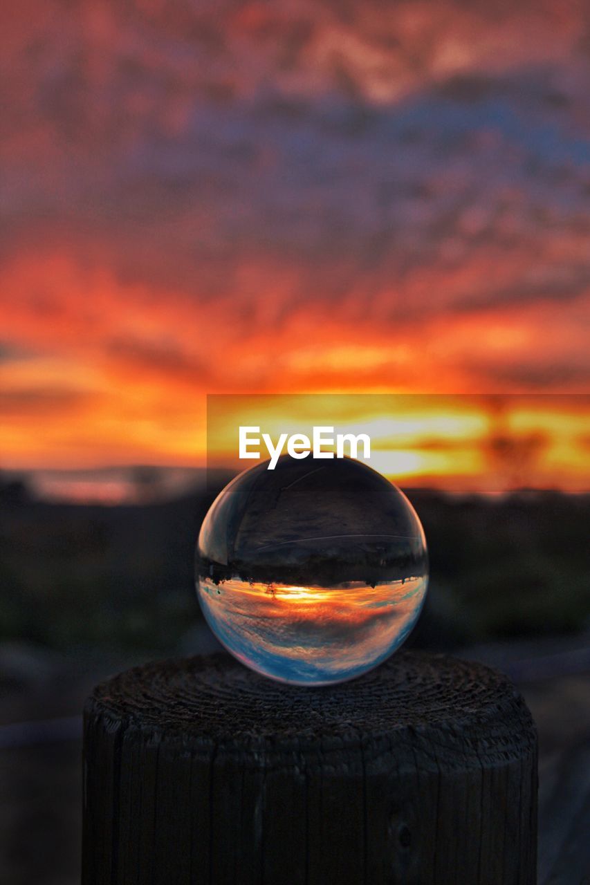 CLOSE-UP OF CRYSTAL BALL AGAINST ORANGE SKY
