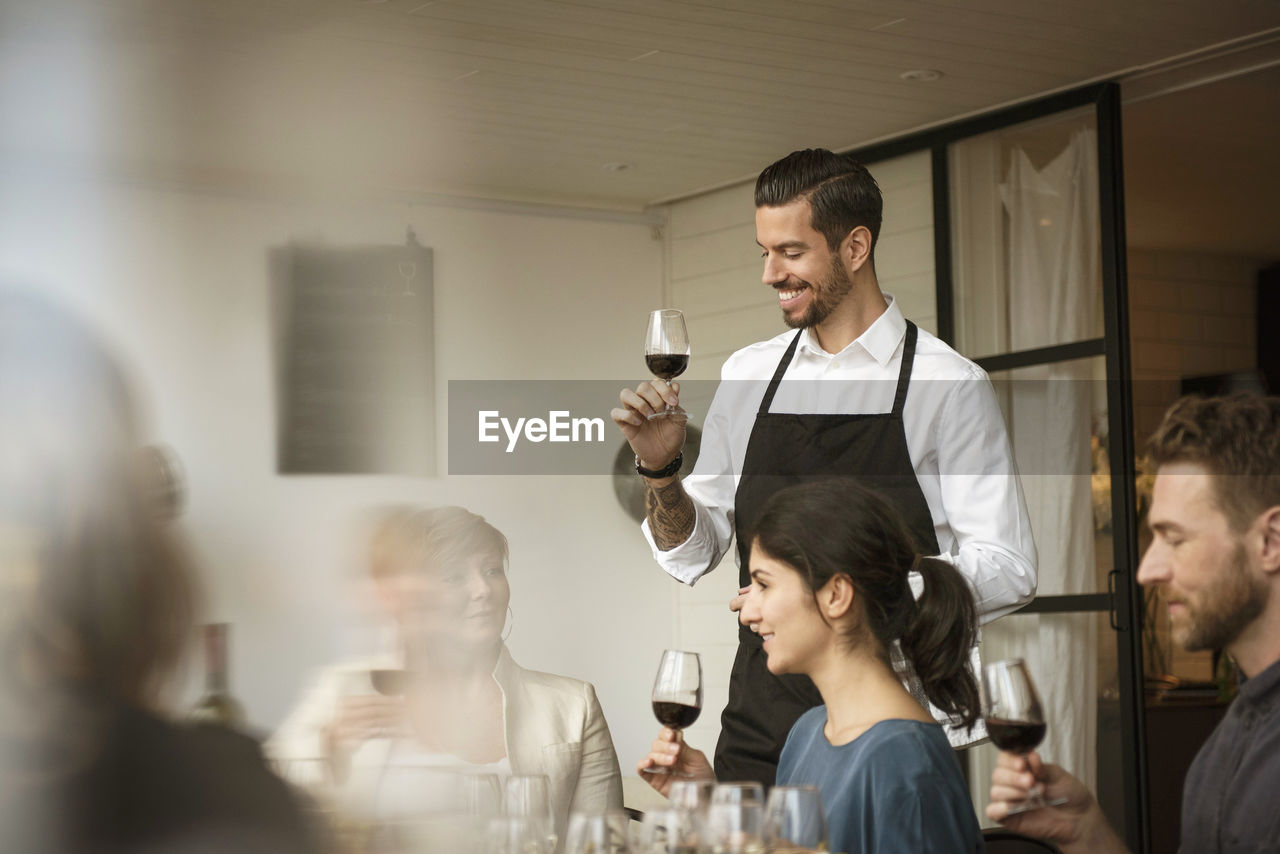 Smiling people holding wineglass while discussing at table