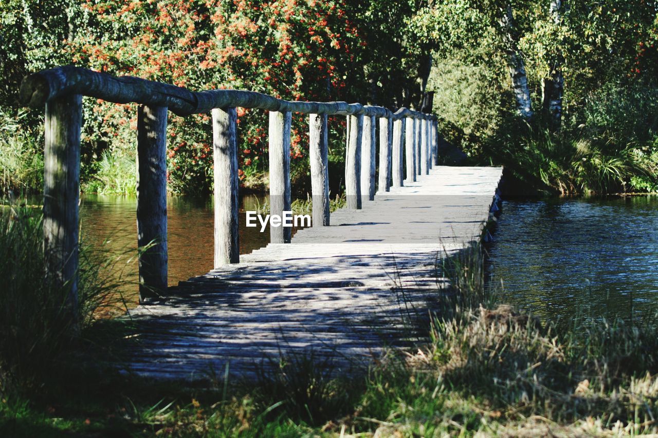 Wooden bridge over river against trees