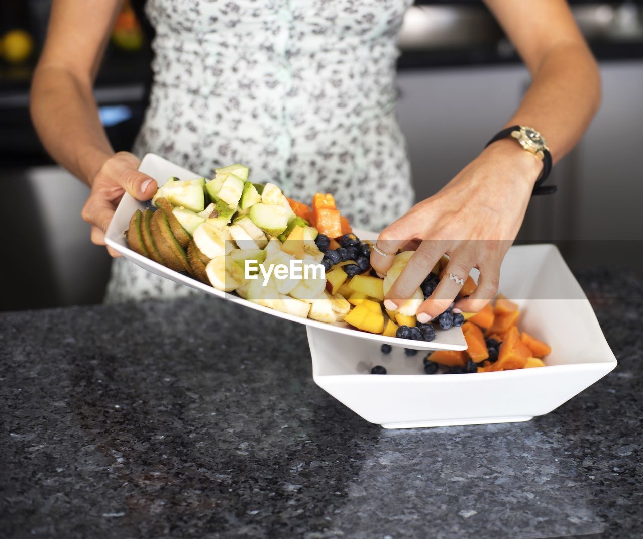 Midsection of woman pouring fruits in bowl