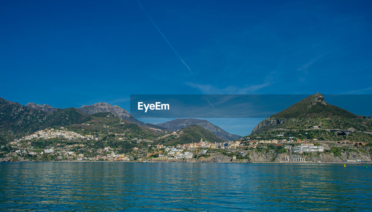 Scenic view of sea and mountains against clear blue sky