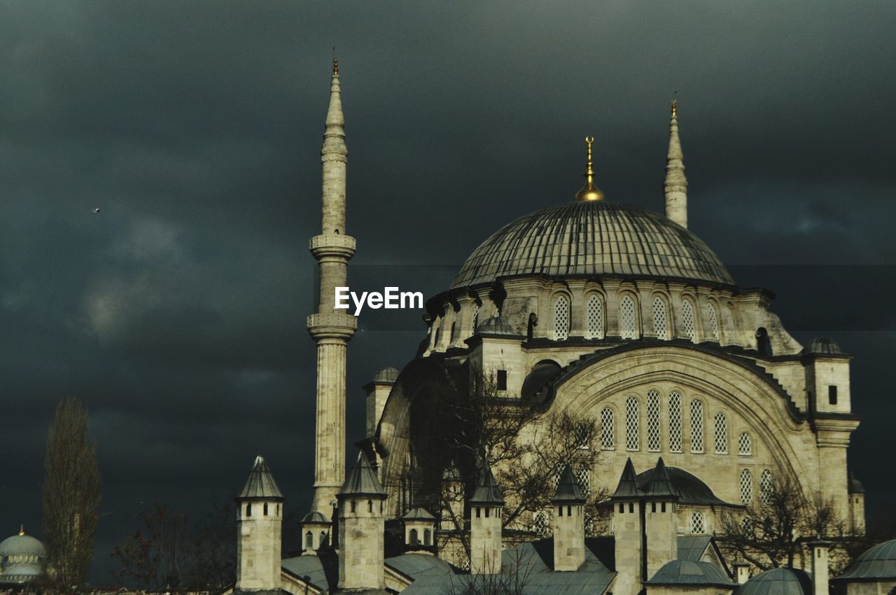 Low angle view of old mosque against cloudy sky