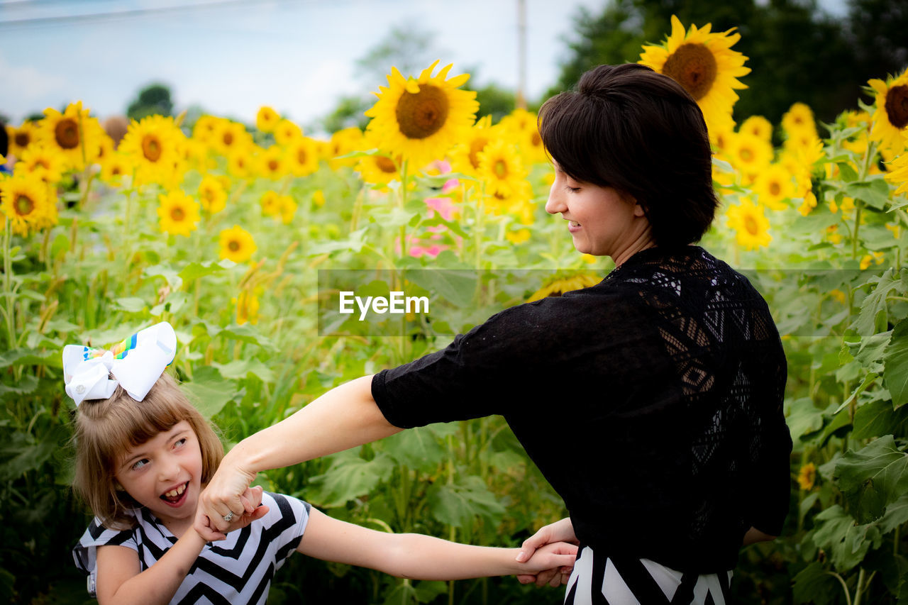 Happy mother and daughter dancing on sunflower field