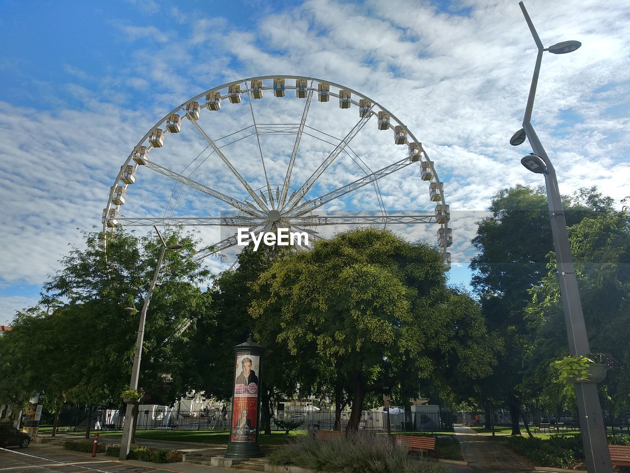 LOW ANGLE VIEW OF FERRIS WHEEL AGAINST TREES