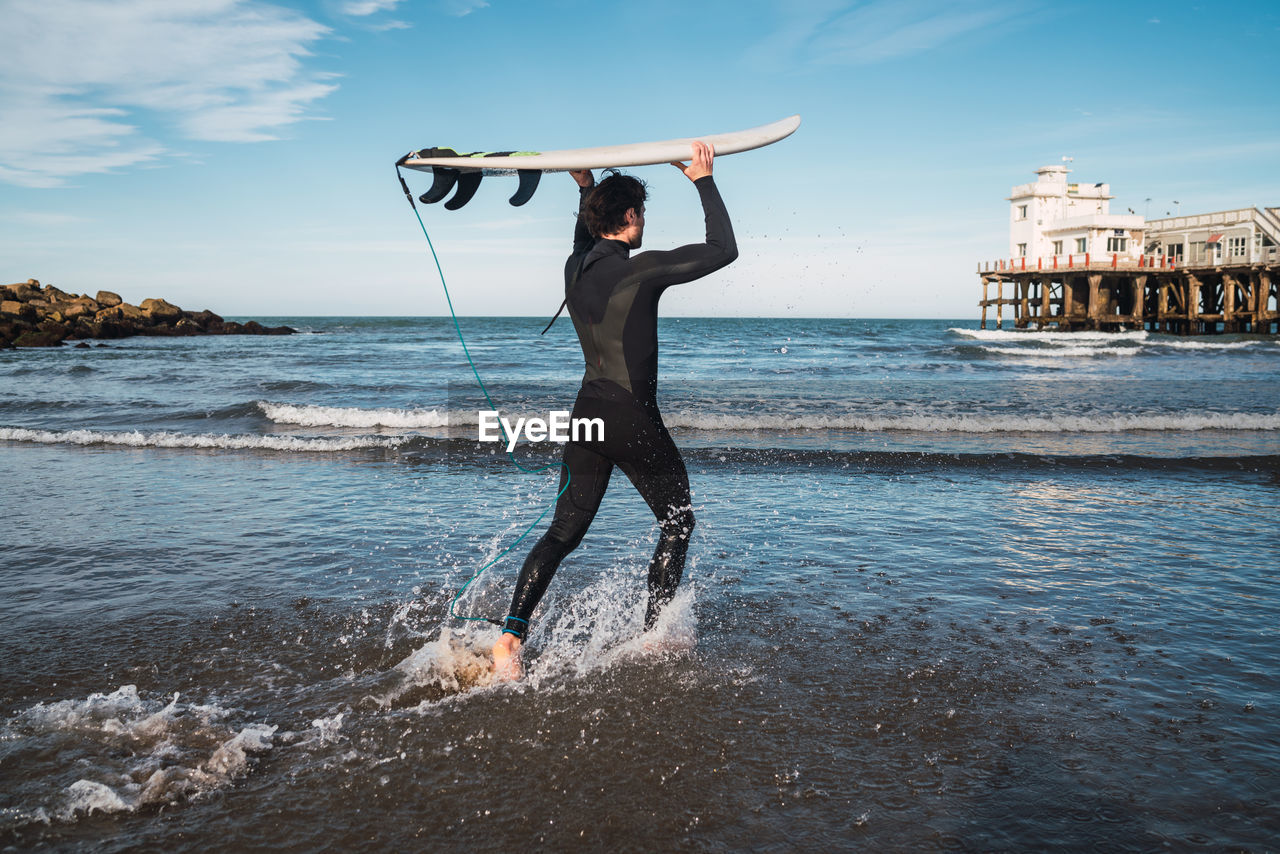 Full length of young man at beach against sky