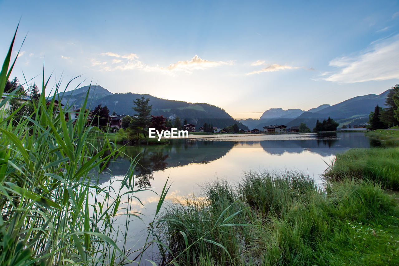 water, nature, sky, lake, mountain, plant, scenics - nature, beauty in nature, environment, grass, reflection, landscape, tranquility, cloud, tranquil scene, mountain range, land, no people, wilderness, reservoir, tree, body of water, travel destinations, travel, natural environment, morning, outdoors, meadow, non-urban scene, beach, idyllic, tourism, blue, summer, trip, holiday, twilight, vacation, day, sunlight
