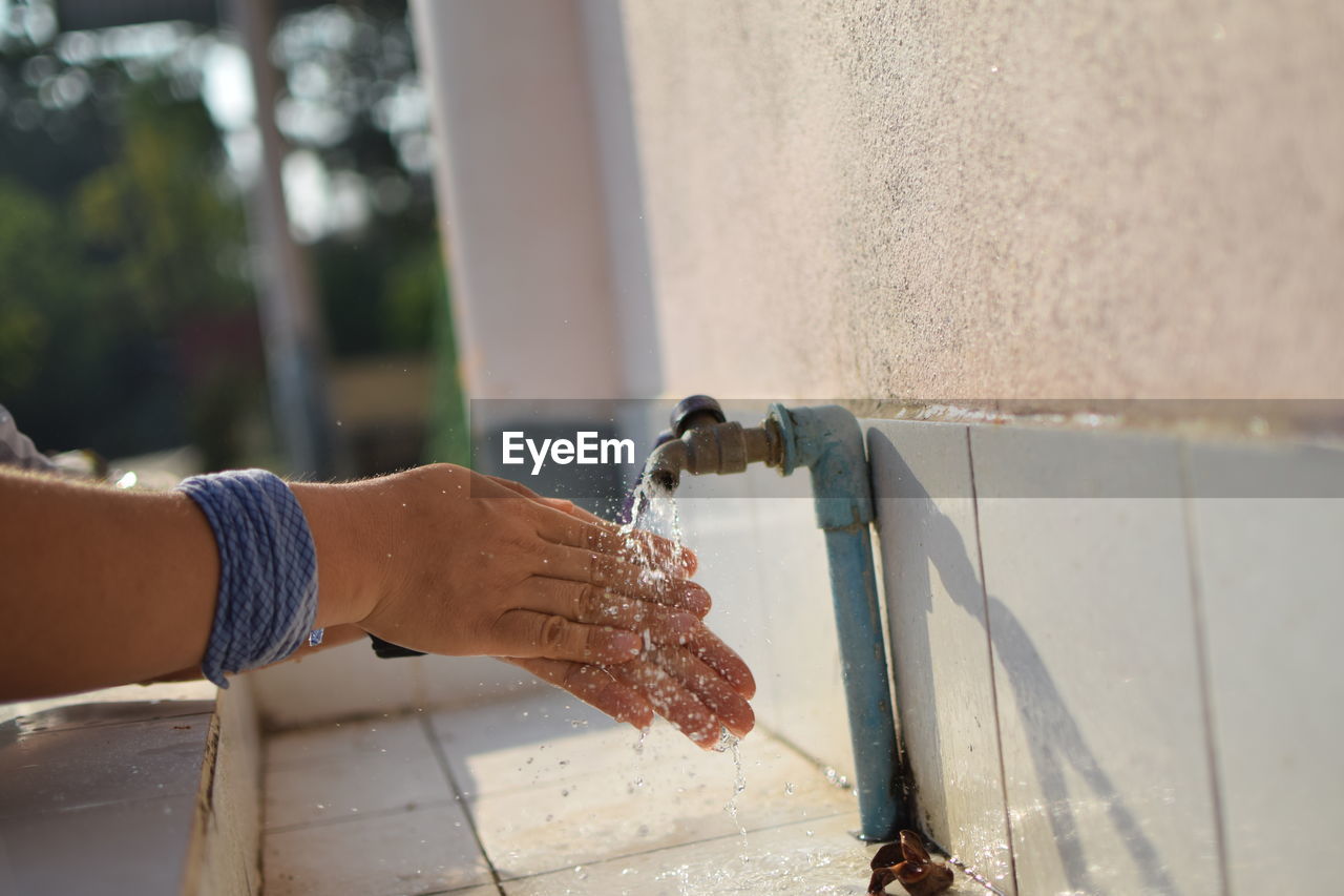 Close-up of hand holding water from faucet