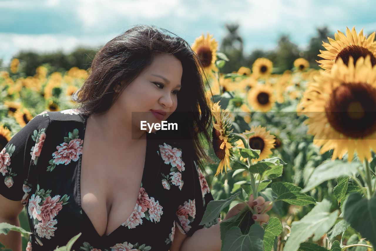 Close-up of woman with sunflowers on field