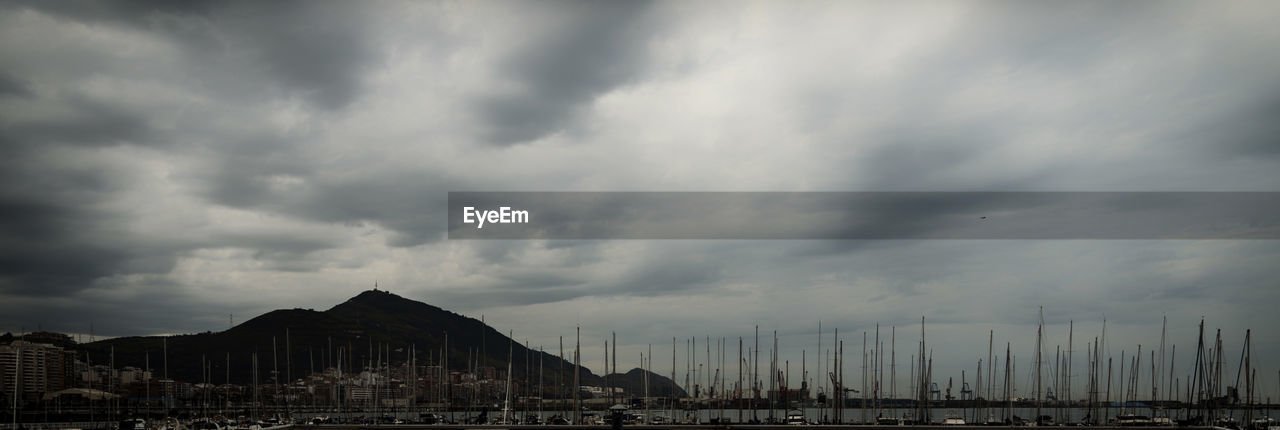 VIEW OF HARBOR AGAINST CLOUDY SKY