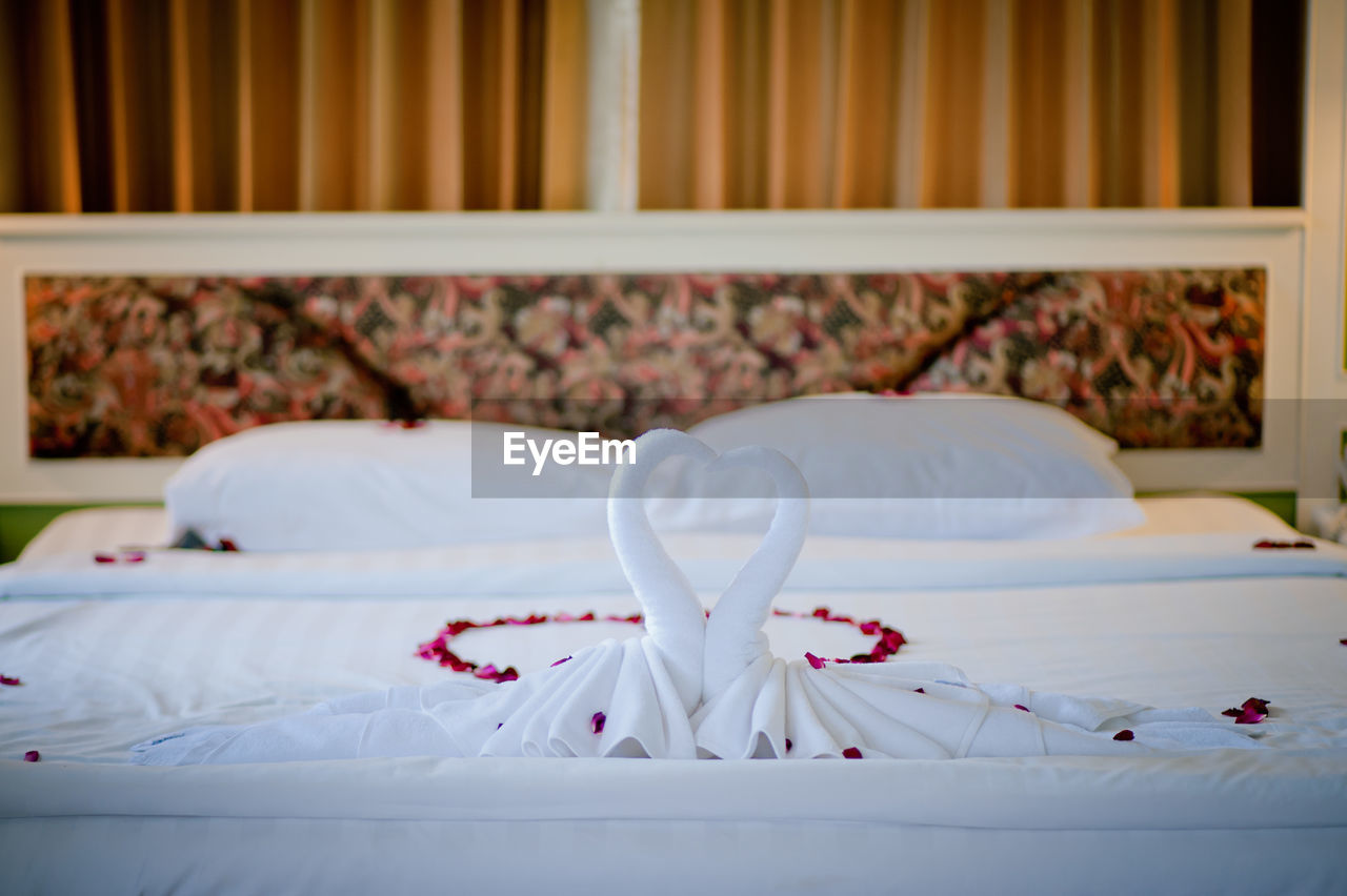Towels in heart shape on bed at home