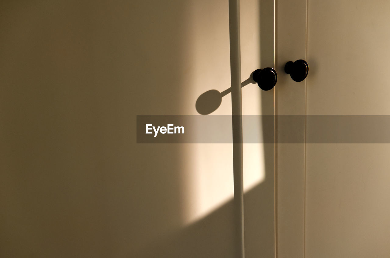 Soft afternoon sunlight falling on closet door with two black doorknobs