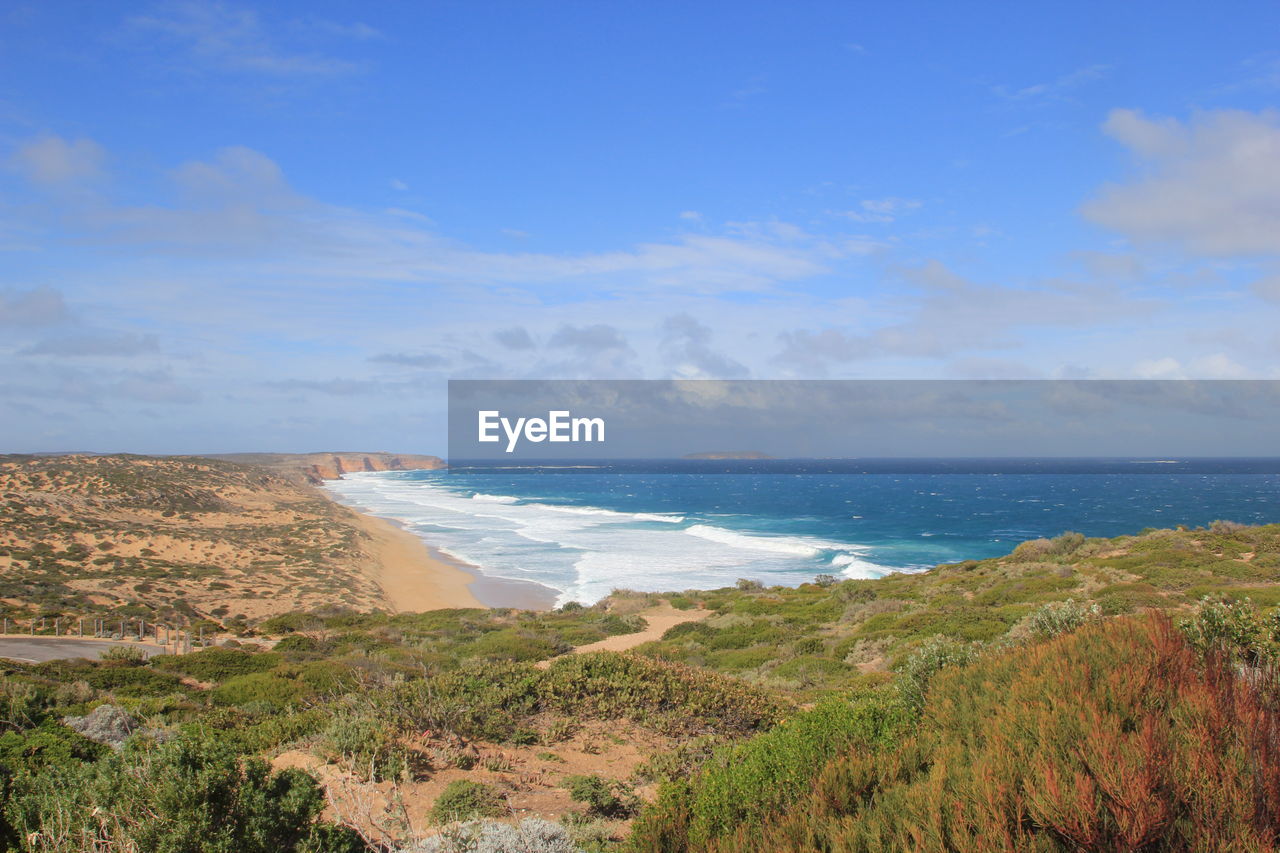 High angle view of calm beach below blue sky