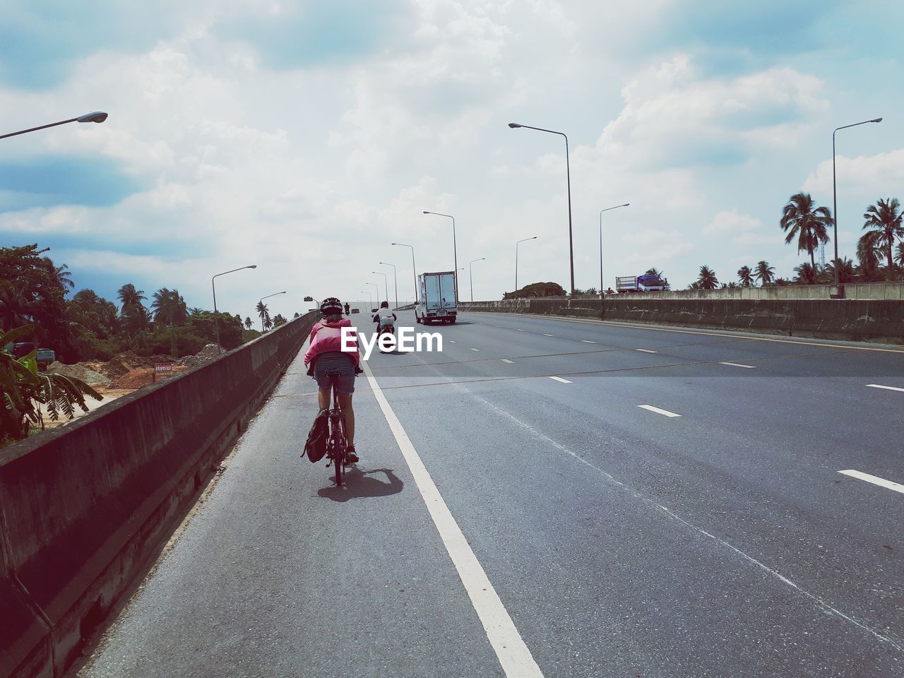 REAR VIEW OF MAN RIDING VEHICLES ON ROAD