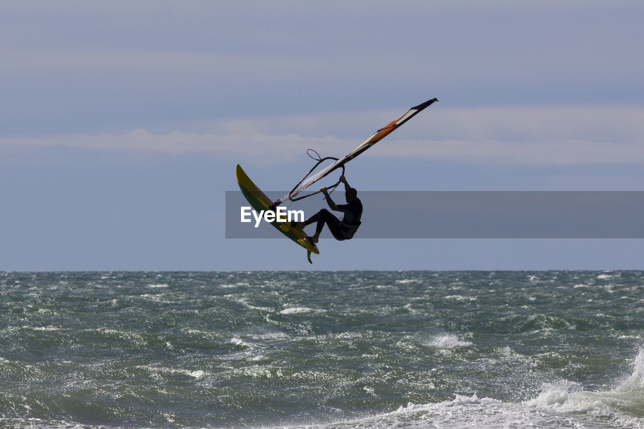 VIEW OF MAN SURFING ON SEA