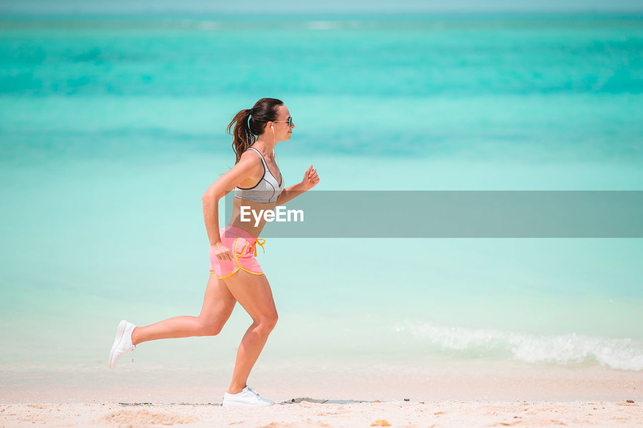 Side view of woman running on beach