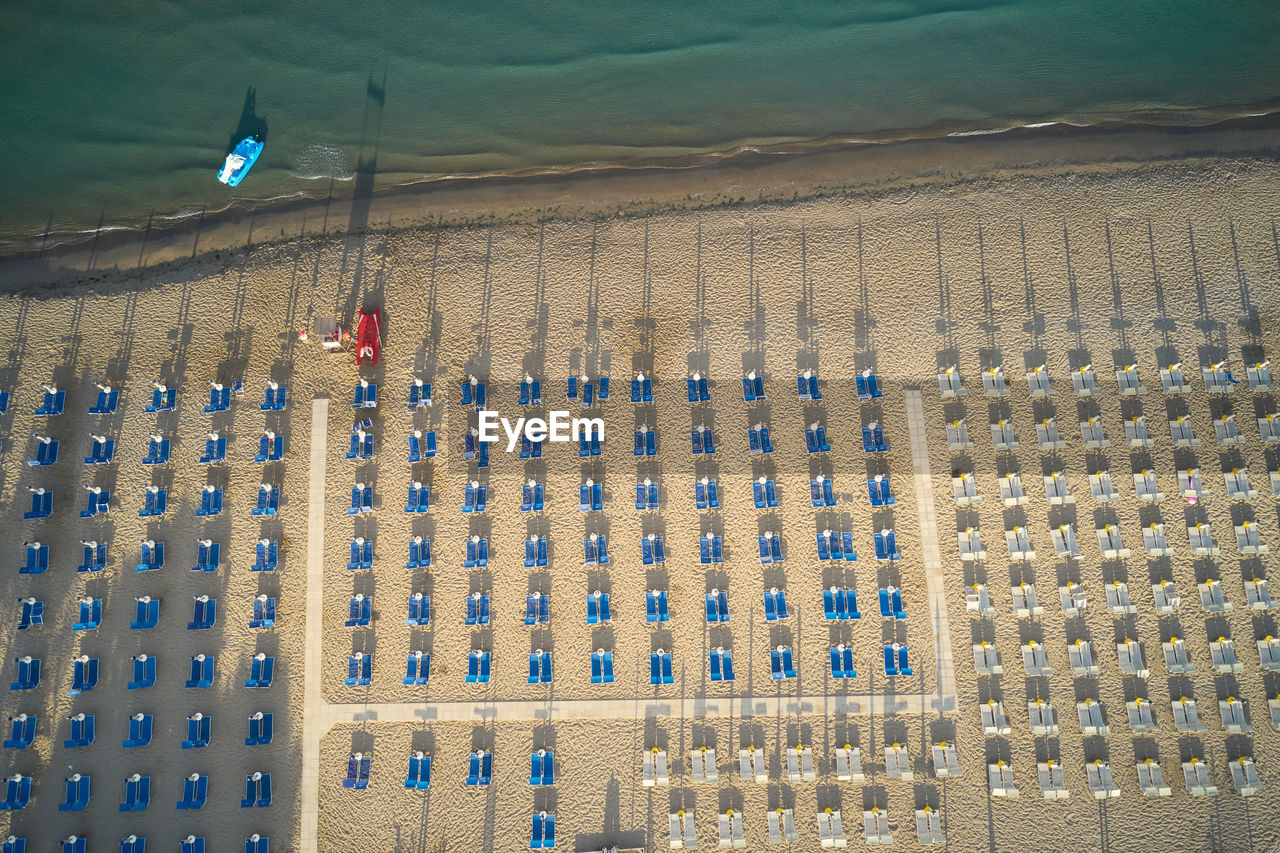 Vertical aerial view of a beach with deck chairs lined up