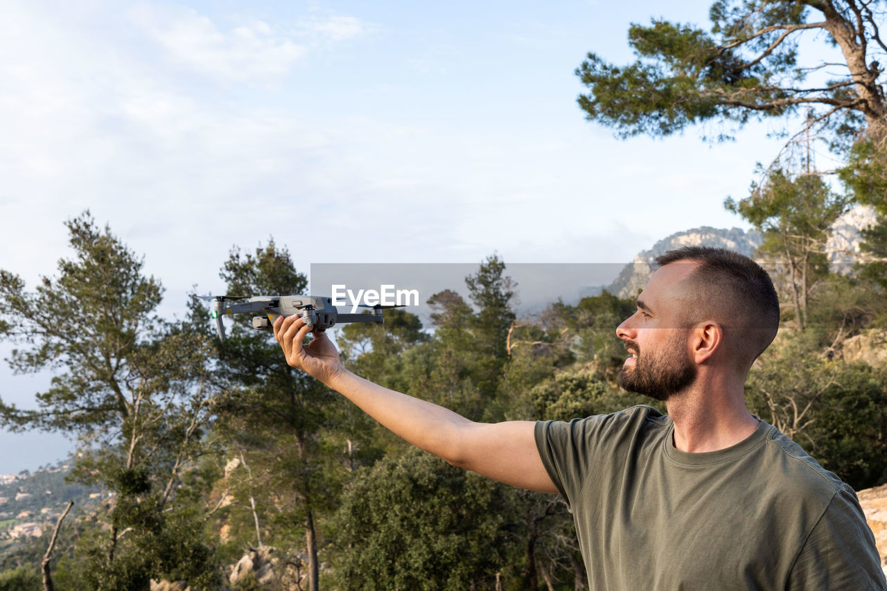 young man photographing through camera against trees