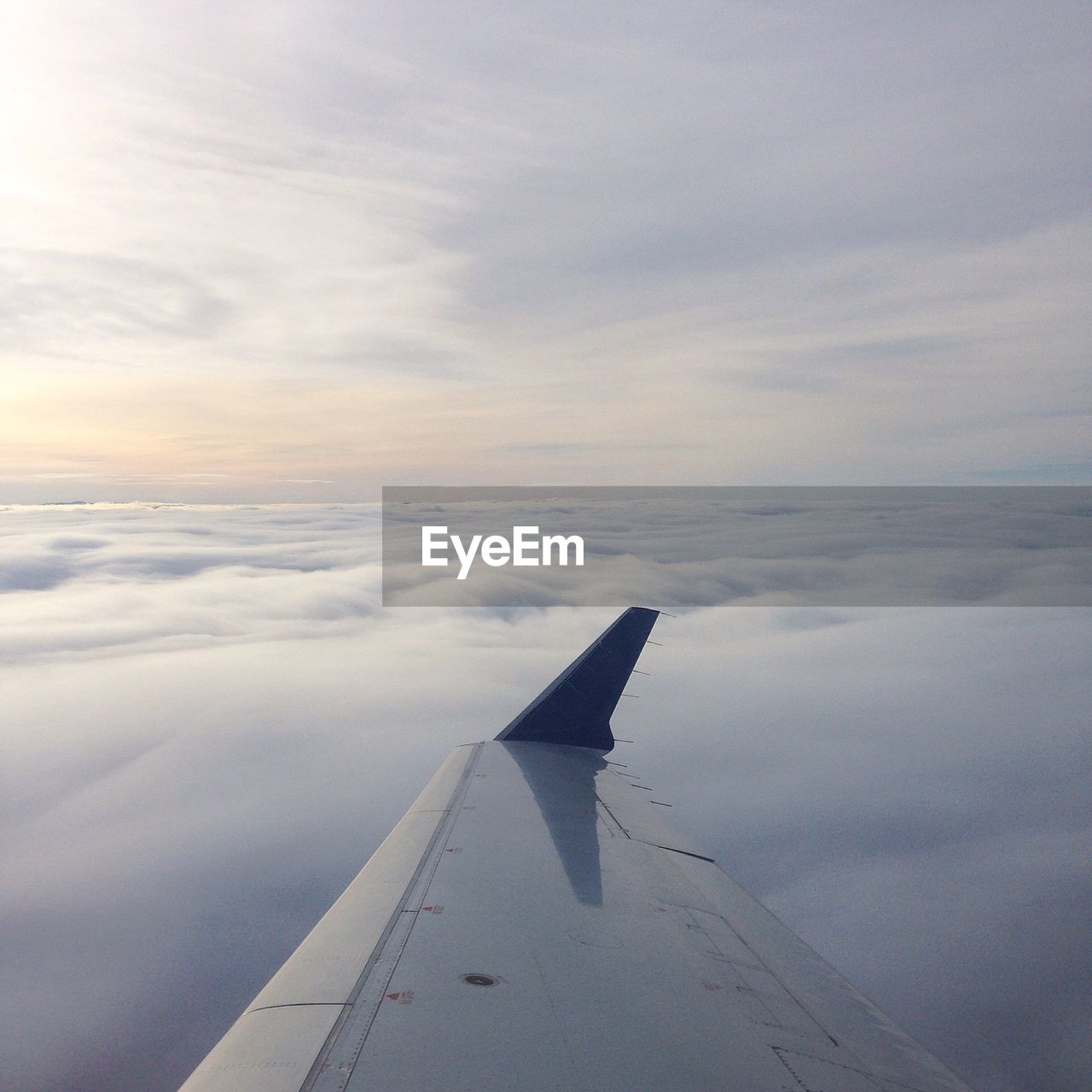 Cropped image airplane wing over cloudscape