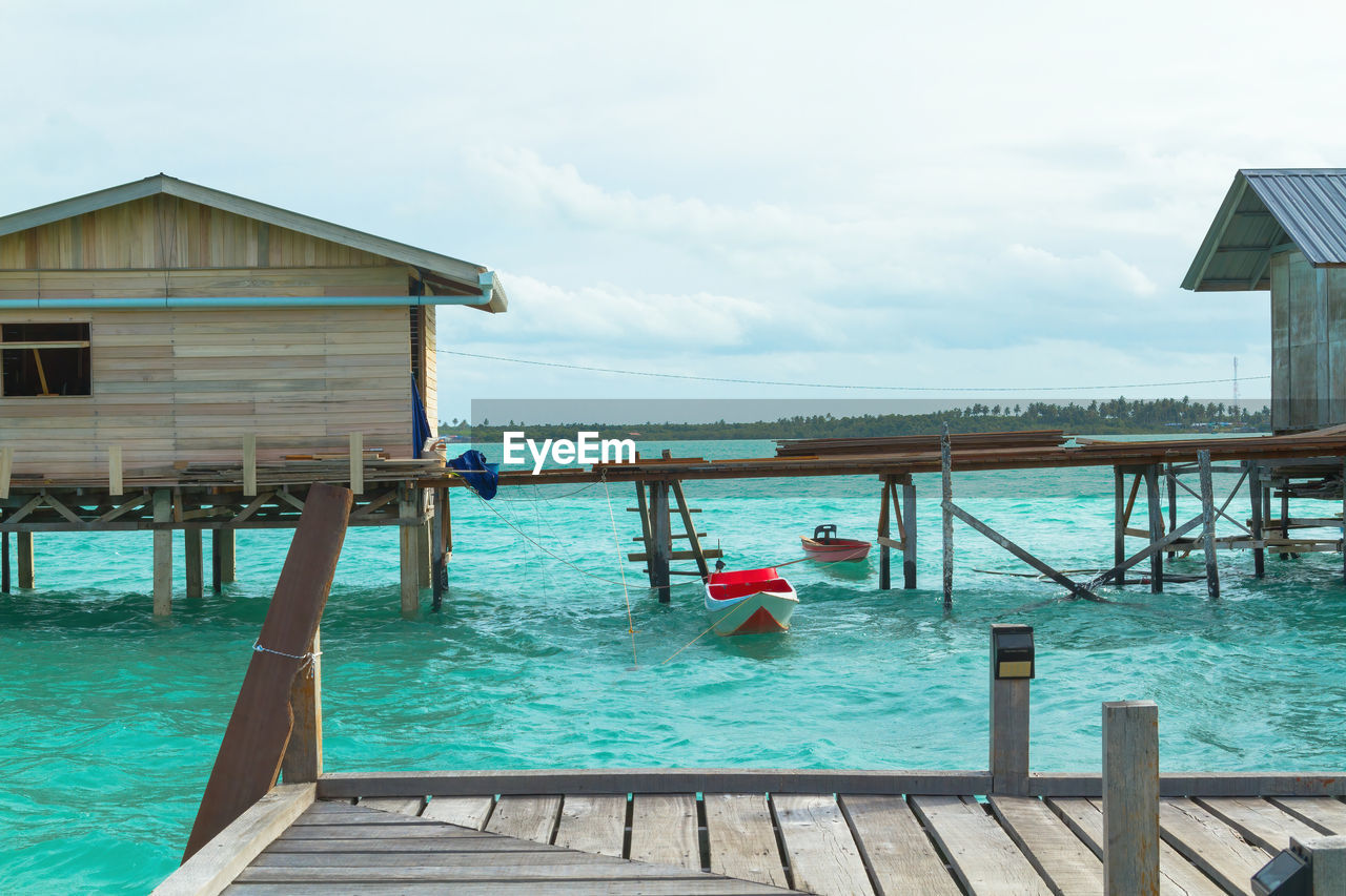 water, vacation, architecture, built structure, wood, sky, nature, sea, building exterior, pier, resort, travel destinations, stilt house, cloud, swimming pool, dock, day, hut, holiday, house, trip, estate, building, beauty in nature, tranquility, no people, scenics - nature, outdoors, travel, land, jetty, beach, tourist resort, tranquil scene, railing, tourism, deck, relaxation, summer, idyllic, residential district, ocean, nautical vessel, sunlight, transportation