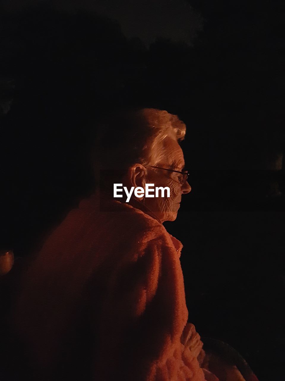 Side view of senior woman camping at night