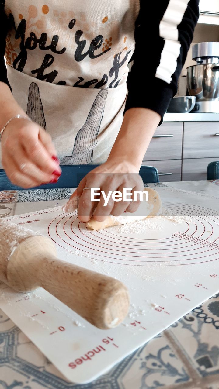 Midsection of woman kneading dough in kitchen