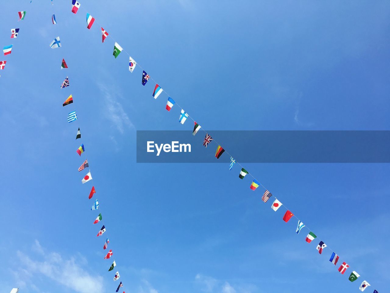 Low angle view of various flags hanging against sky