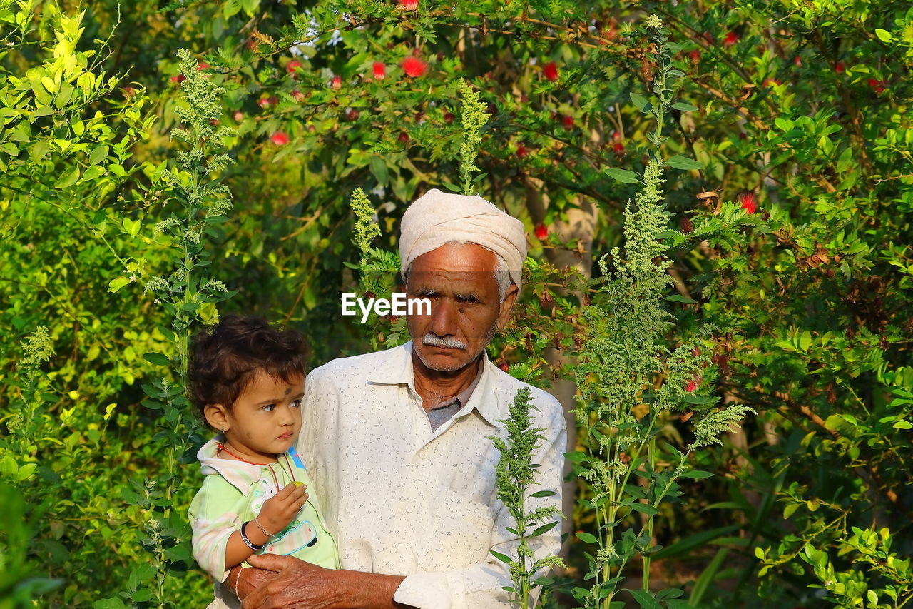 Grandfather and little child standing in the home garden , india