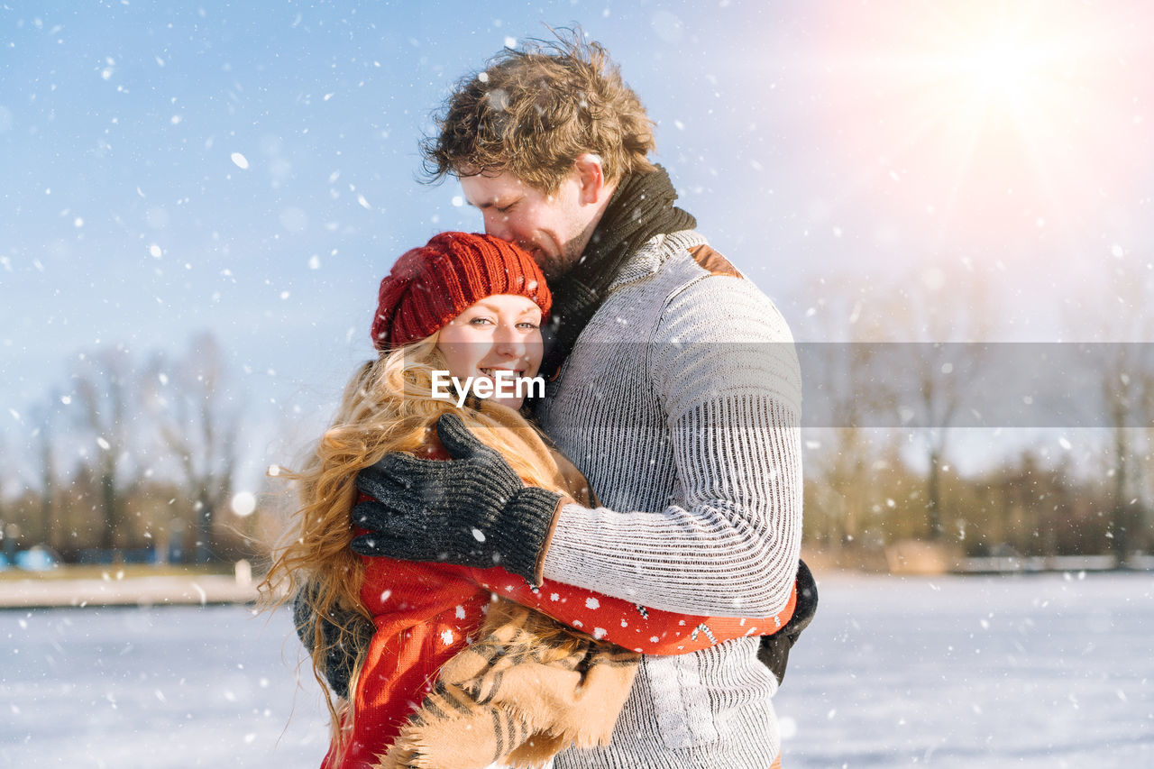 Smiling girl with boyfriend standing outdoors during winter