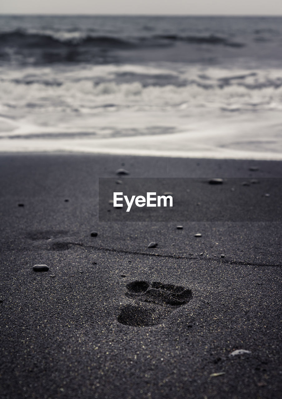 Footprints on sand at beach against sky