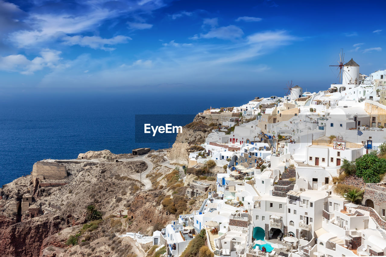 High angle view of buildings on mountain by sea against sky