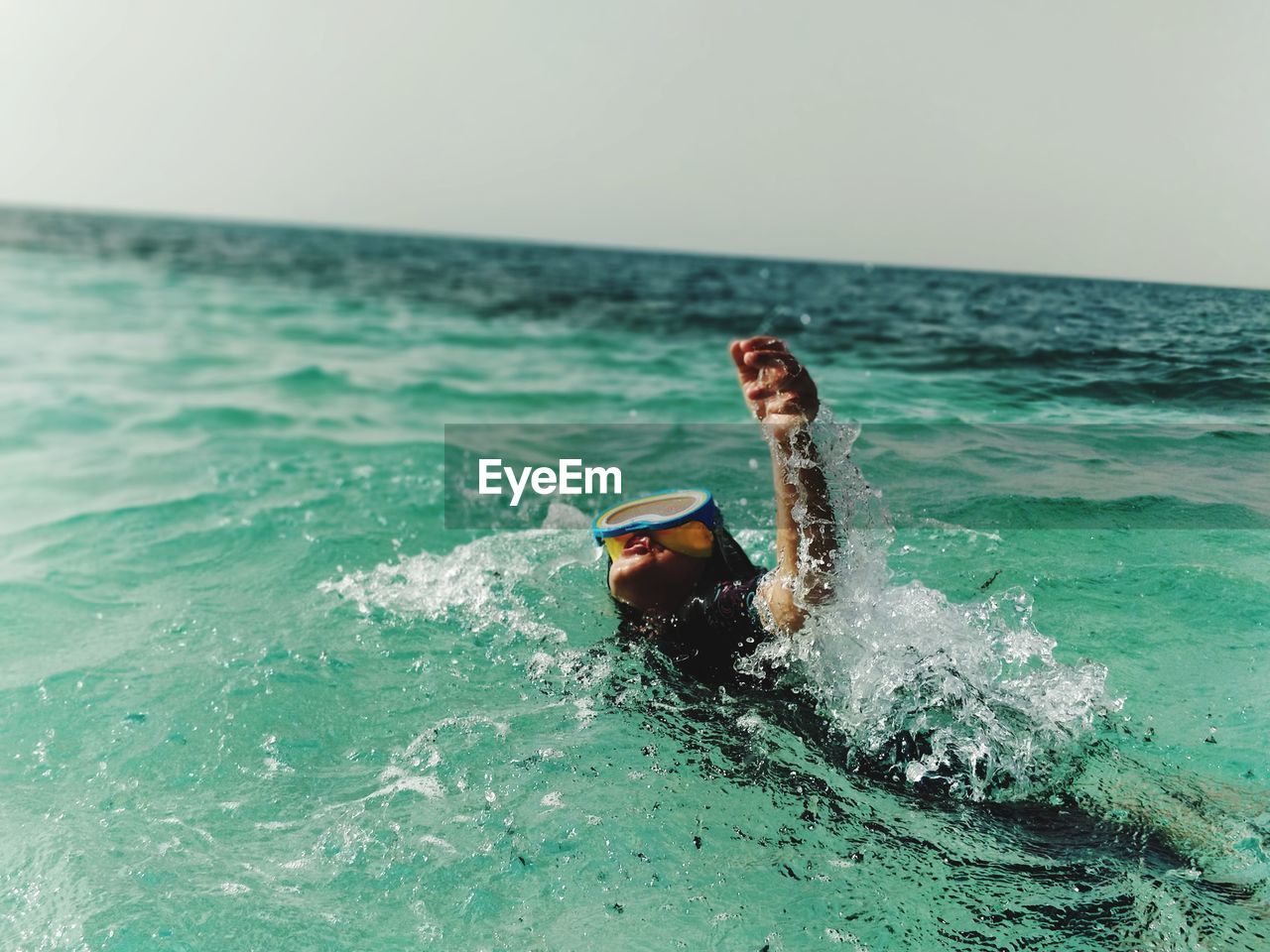 Girl swimming in sea against sky