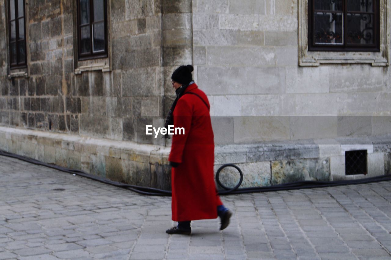 FULL LENGTH REAR VIEW OF A MAN WALKING ON ROAD