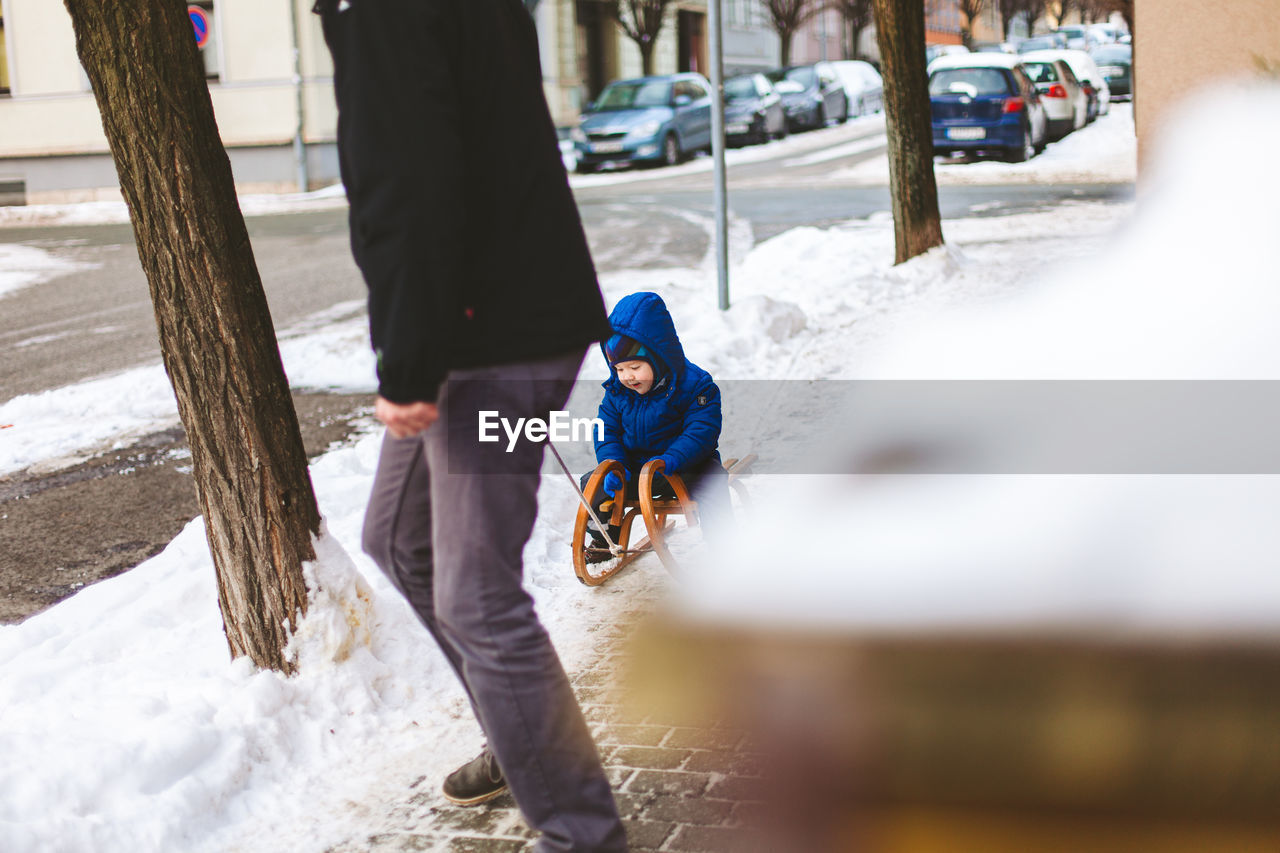 Rear view of boy riding sleigh in winter