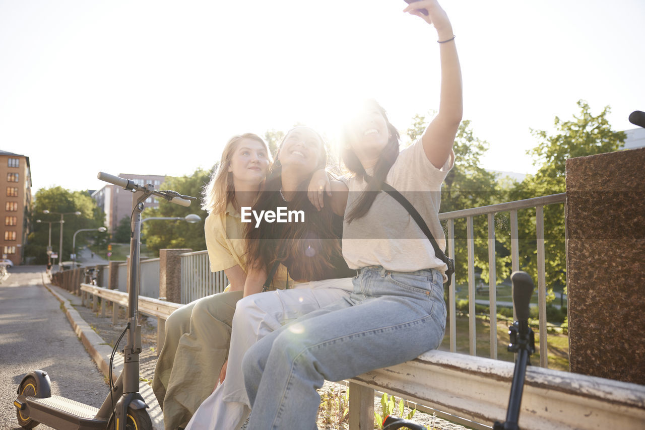 Young female friends spending time together outdoors and taking selfie