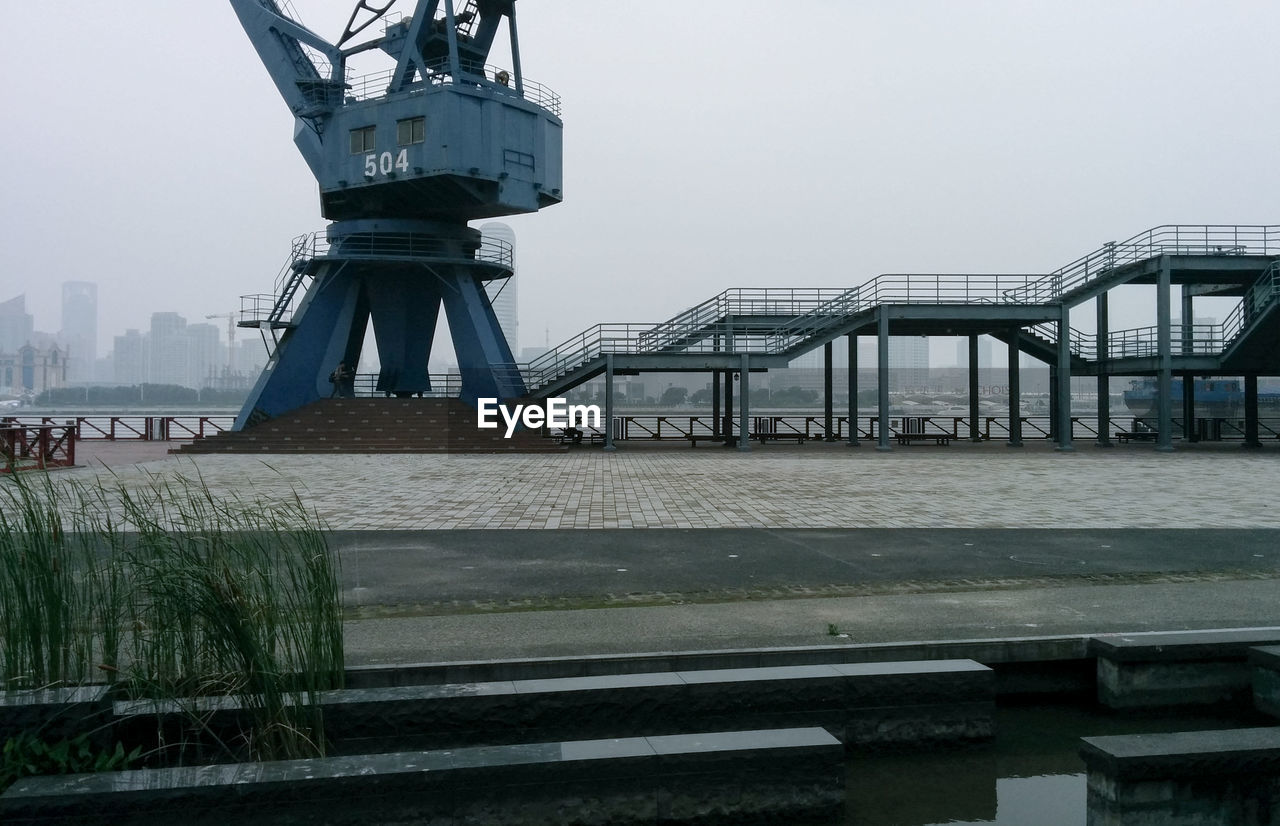 Crane at dock against sky