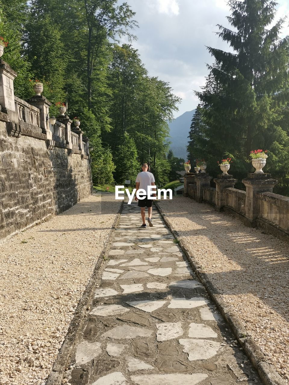 REAR VIEW OF MAN WALKING ON WALKWAY